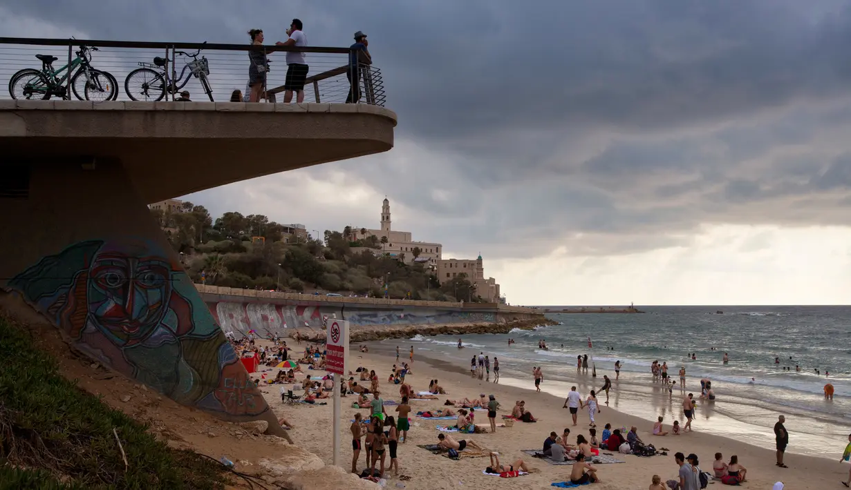 Wisatawan menghabiskan waktu di pantai dekat Pelabuhan Jaffa, Israel, 21 Juli 2018. Pelabuhan Jaffa menghadap ke Laut Mediterania dan memiliki tanah yang subur. (AP Photo/Oded Balilty)