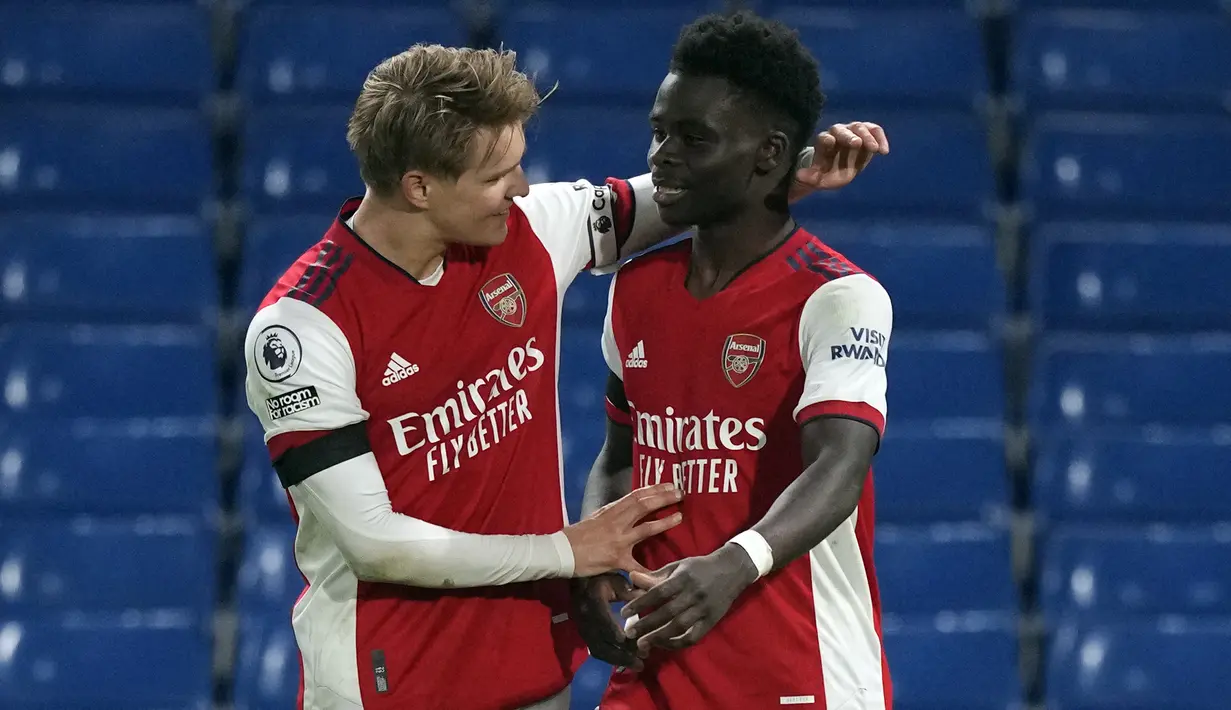 Pemain Arsenal Bukayo Saka (kanan) mendapat selamat dari rekan setimnya Martin Odegaard setelah dia mencetak gol ke gawang Chelsea pada pertandingan sepak bola Liga Inggris di Stamford Bridge, London, Inggris, 20 April 2022. Arsenal menang 4-2. (AP Photo/Frank Augstein)