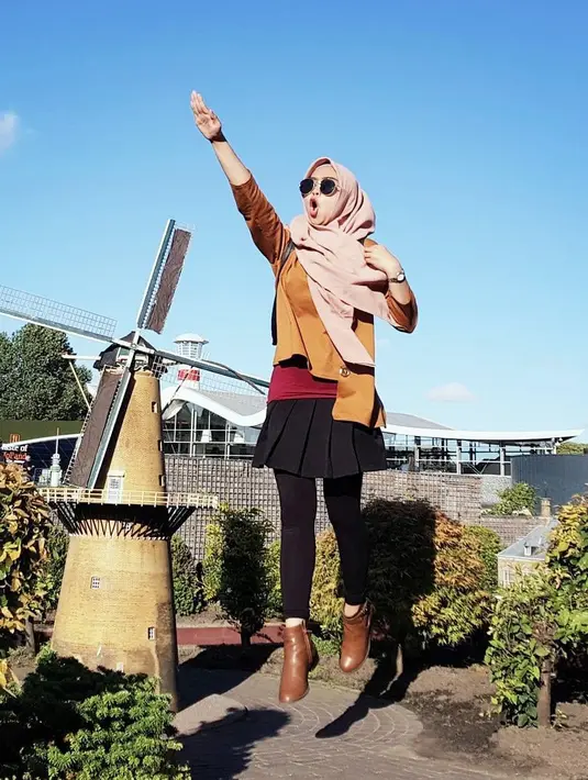 Gadis kelahiran tahun 1995 ini terlihat bahagia saat liburan ke Belanda. Menggunakan pakaian padu padan warna cokelat dan hitam, ditambah dengan hijab berwarna krem membuat penampilannya semakin mengagumkan. Posenya selalu ceria. (Liputan6.com/IG/@riaricis1795)