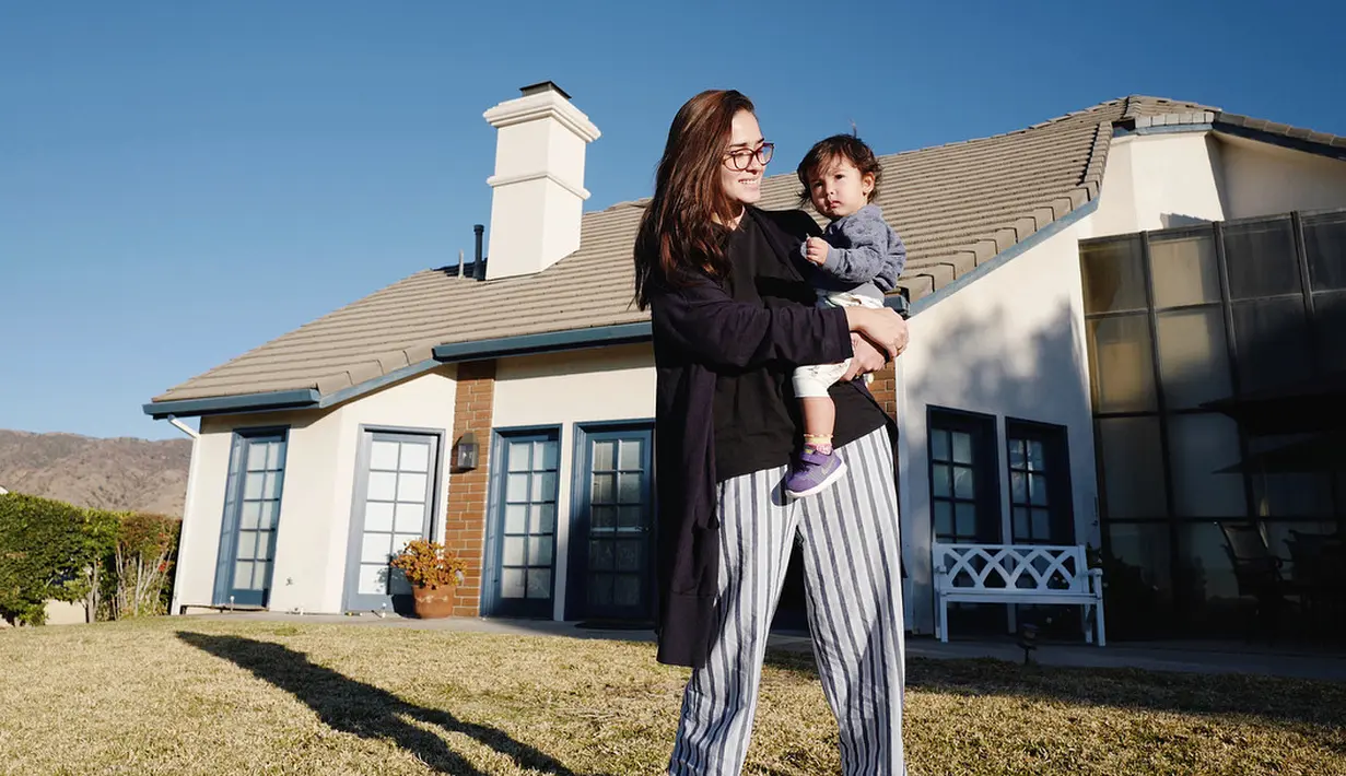 Tengah menggendong buah hati seperti di foto ini, tampilan Yasmine tetap memukau. Gayanya super simple, hanya memakai celana bermotif garis-garis dengan blus hitam sebagai atasannya. (Instagram/yaswildblood)
