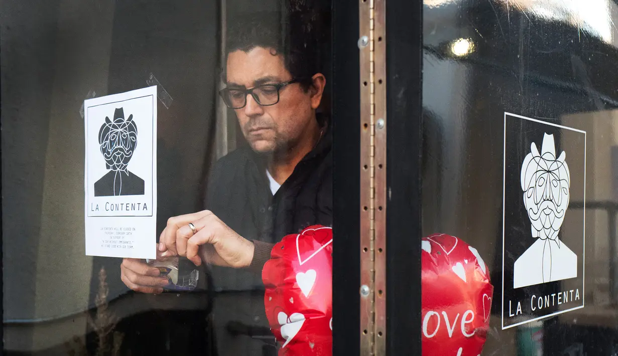 Luis Arce Mota menempel tanda pemberitahuan tutup saat Sehari Tanpa Imigran di kaca restorannya di New York, Kamis (16/2). 'Hari Tanpa Imigran' dilakukan untuk menunjukkan amat pentingnya peran para imigran bagi perekonomian di AS (AP Photo/Mark Lennihan)