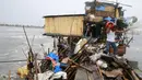 Keluarga Taroyo yang tinggal di sepanjang pantai Teluk Manila mencari barang yang bisa diselamatkan setelah rumah mereka rusak akibat Topan Koppu, Minggu (18/10). Topan Koppu melanda Filipina timur laut dan merusak rumah-rumah. (REUTERS/Romeo Ranoco)
