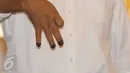 Cagub DKI Anies Baswedan menunjukkan jarinya yang telah dicelup tinta sambil berpose salam tiga jari di TPS 028 Cilandak Barat, Jakarta, Rabu (15/2). Anies datang bersama istri, Fery Farhati dan anak perempuannya. (Liputan6.com/Immanuel Antonius)