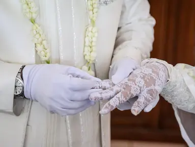 Pengantin pria memasangkan cincin ke pasangannya usai akad nikah di KUA Jagakarsa, Jakarta, Sabtu (6/6/2020). Pada masa penerapan PSBB transisi, pihak KUA tersebut menikahkan sebanyak delapan hingga 10 pasangan pengantin per hari. (Liputan6.com/Faizal Fanani)