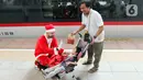 Pekerja yang mengenakan kostum Sinterklas membagikan hadiah Natal kepada penumpang kereta cepat Whoosh. (Liputan6.com/Herman Zakharia)