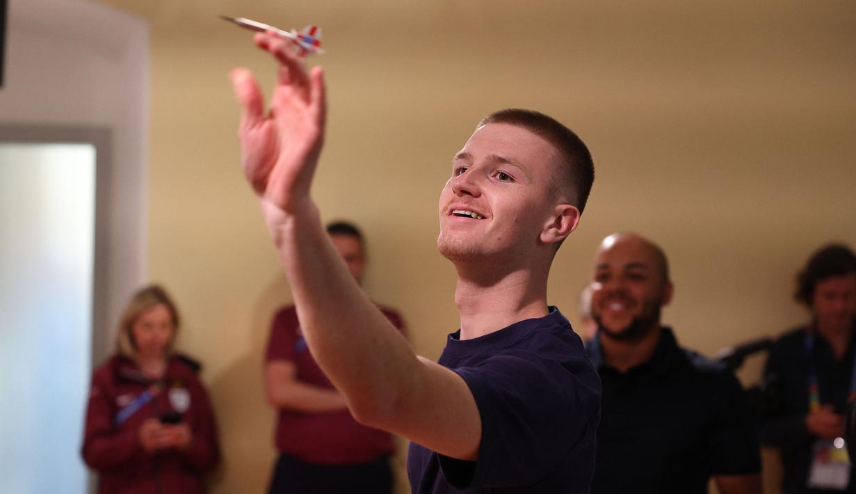 Pemain muda Timnas Inggris, Adam Wharton bermain Darts melawan jurnalis saat konferensi pers menjelang Euro 2024 di Blankenhain, Thuringia, Rabu (12,/06/2024) waktu setempat. (AFP/Adrian Dennis)