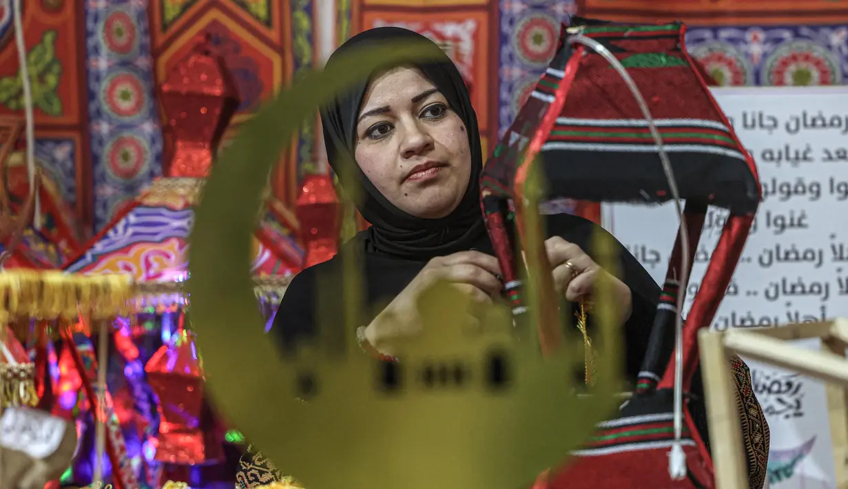 Perajin Palestina, Reham Shurab membuat lentera tradisional "fanous" untuk dekorasi menjelang bulan suci Ramadan, di bengkel rumahnya di Khan Yunis di Jalur Gaza Selatan pada Senin 13 Maret 2023. Selain lentera tradisional "fanous", beberapa rumah juga ada yang menambahkan dekorasi berbentuk bulan sabit dan bintang, lambang agama Islam. (SAID KHATIB/AFP)