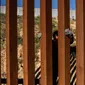 Kevin Andres, seorang anak imigran Meksiko berusaha memanjat pagar perbatasan AS (28/12). Banyak Imigran dari karavan memilih menyeberangi tembok perbatasan AS dan menyerahkan diri kepada agen patroli perbatasan. (AP Photo/Daniel Ochoa de Olza)