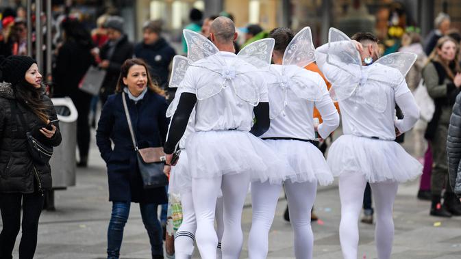 Sekelompok pria mengenakan kostum di jalanan pusat perbelanjaan saat puluhan ribu orang menyambut dimulainya musim karnaval di jalan-jalan Kota Cologne, Jerman, Senin (11/11/2019). Musim karnaval ini dikenal juga sebagai musim kelima dalam satu tahun. (AP Photo/Martin Meissner)