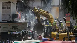 Petugas keamanan dan penyelamat menggunakan alat berat untuk mengevakuasi bangunan yag runtuh di Mumbai, India (31/8). Menurut pejabat setempat, sekitar 40 orang terjebak dalam reruntuhan bangunan tersebut. (AP Photo / Rafiq Maqbool)