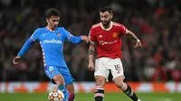 Gelandang Manchester United atau MU Bruno Fernandes bersaing dengan striker Atletico Madrid Antoine Griezmann pada leg kedua babak 16 besar Liga Champions di Old Trafford, Rabu (16/3/2022) dini hari WIB. (Paul ELLIS / AFP)