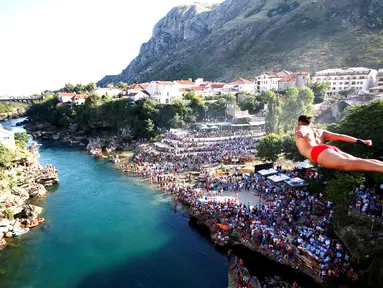 Peserta pria beraksi dengan melompat dari jembatan saat mengkuti acara kompetisi menyelam tradisional 450 di Mostar, Bosnia dan Herzegovina, (31/7). (REUTERS/Dado Ruvic)