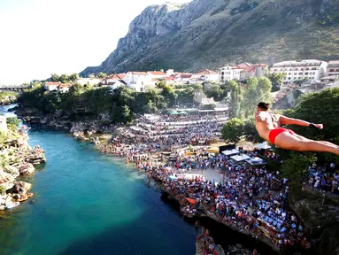 Peserta pria beraksi dengan melompat dari jembatan saat mengkuti acara kompetisi menyelam tradisional 450 di Mostar, Bosnia dan Herzegovina, (31/7). (REUTERS/Dado Ruvic)