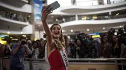 Miss Universe 2017 asal Afrika Selatan, Demi-Leigh Nel-Peters berselfie dengan awak media saat tiba di Bandara Internasional OR Tambo di Johannesburg (24/1). (AFP Photo/Gulshan Khan)