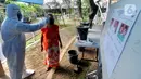 Petugas dengan memakai baju hazmat mengukur suhu warga sebelum mencoblos dalam Pilkada Tangerang Selatan 2020 di TPS 46, Paku Jaya, Serpong Utara, Rabu (9/12/2020). Para petugas KPPS di TPS 46 ini mengunakan seragam APD untuk mengantisipasi penyebaran COVID-19. (merdeka.com/Arie Basuki)
