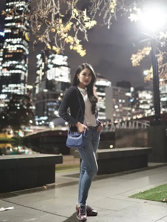Kombinasi black cardigan, white turtleneck top, dan skinny jeans juga tak kalah menarik. Sandra Dewi melengkapi penampilannya dengan sneakers warna hitam dan sling bag warna biru. (Instagram/sandradewi88).