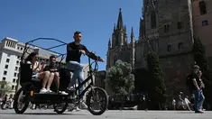 Turis menikmati perjalanan dengan ojek di Plaza de la Catedral di Barcelona, ​​​​pada 11 Mei 2022. Pengunjung sekali lagi memadati jalan-jalan sempit di kawasan Gothic Barcelona yang sempit saat perjalanan global bangkit kembali dari pandemi COVID-19, menghidupkan kembali kekhawatiran atas pariwisata massal di kota pelabuhan Spanyol. (LLUIS GEN / AFP)
