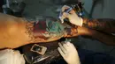 Seorang seniman terlihat serius menato seorang wanita dibagian kakinya saat Festival Internasional Tattoo Week Rio 2016 ketiga di Rio de Janeiro, Brasil, (22/1/2016). (REUTERS/Pilar Olivares)