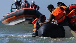 Migran berusaha menaiki perahu milik penyelundup dari pantai Equihen-Plage, Prancis utara, Rabu (23/9/2026), untuk menyeberangi Selat Inggris menuju Inggris. Pada hari yang sama, jenazah seorang pria ditemukan di Pantai Neufchâtel-Hardelot, Pas-de-Calais, setelah upaya keberangkatan sejumlah migran. Petugas pemadam kebakaran menyatakan pria tersebut meninggal dunia tak lama setelah pukul 09.00 waktu setempat. (Sameer Al-DOUMY / AFP)