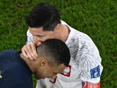 Striker Polandia, Robert Lewandowski kembali kedapatan berbisik akrab di akhir laga dengan pemain lawan dalam ajang Piala Dunia 2022. Setelah sebelumnya Lionel Messi yang diajaknya berbicara dengan cara berbisik-bisik usai laga Polandia kontra Argentina, kini giliran bintang Prancis Kylian Mbappe yang diajaknya berbisik usai Polandia disingkirkan Prancis dalam babak 16 besar, Minggu (4/12/2022) malam WIB. Tentu saja hobi baru Lewandowski dengan berbisik di akhir laga tersebut menjadi menarik, karena dilakukan terhadap dua pemain yang kini sedang membela PSG. (AFP/Manan Vatsyayana)