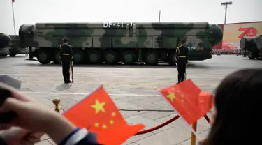 Warga mengibarkan bendera China saat kendaraan militer yang membawa Dongfeng-41 atau DF-41 melintas dalam parade militer di Beijing, 1 Oktober 2019. Rudal balistik antarbenua DF-41 menjadi sorotan pengamat dan ahli persenjataan dunia karena disebut dapat menjangkau wilayah AS. (AP/Mark Schiefelbein)