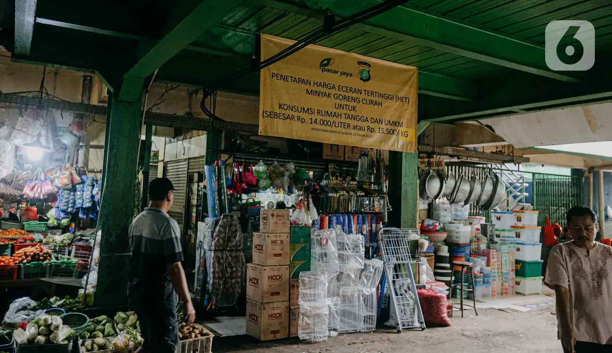 Pedagang melintas di dekat spanduk terkait penetapan harga minyak goreng subsidi di lorong Pasar Kramat Jati, Jakarta, Senin (30/5/2022). Adanya spanduk minyak goreng subsidi tersebut  untuk mensosialisasikan soalnya Per 31 Mei 2022 pemerintah berencana mencabut subsidi minyak goreng curah. (Liputan6.com/Faizal Fanani)
