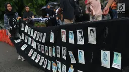 Aktivis bersiap menggulung deretan foto korban saat aksi Kamisan ke-562 di depan Istana Merdeka, Jakarta, Kamis (15/11). Mereka meminta pemerintah menyelesaikan kasus pelanggaran HAM berat khususnya Tragedi Semanggi 1. (Liputan6.com/Helmi Fithriansyah)
