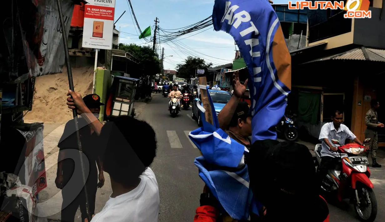 Petugas Pemda tampak mencopot bendera parpol yang dipasang di tiang listrik sekitar kawasan Mampang (7/4/2014) (Liputan6.com/Johan Tallo).