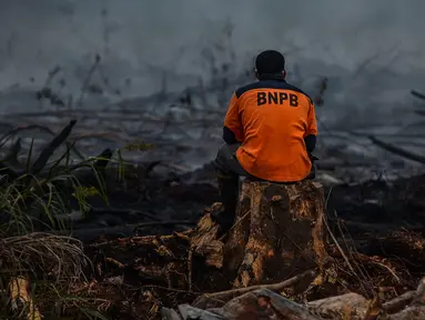 Petugas pemadam kebakaran beristirahat usai memadamkan kebakaran lahan gambut di Kampar, Riau, Senin (9/9/2019). Sulitnya sumber air di lokasi kebakaran menjadi kendala petugas untuk memadamkan bara api yang menghanguskan sedikitya lima hektare lahan gambut di kawasan tersebut.  (Wahyudi / AFP)