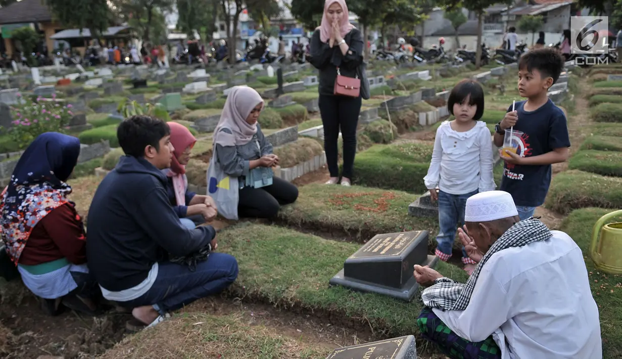 Sebuah keluarga menggelar doa 'Talkin' yang dipimpin oleh Muhammad Hoir di TPU Kemiri, Rawamangun, Jakarta, Selasa (15/5). Setiap tahunnya, Hoir datang ke TPU Kemiri seminggu sebelum puasa dan kembali lagi setelah Lebaran. (Merdeka.com/Iqbal S Nugroho)