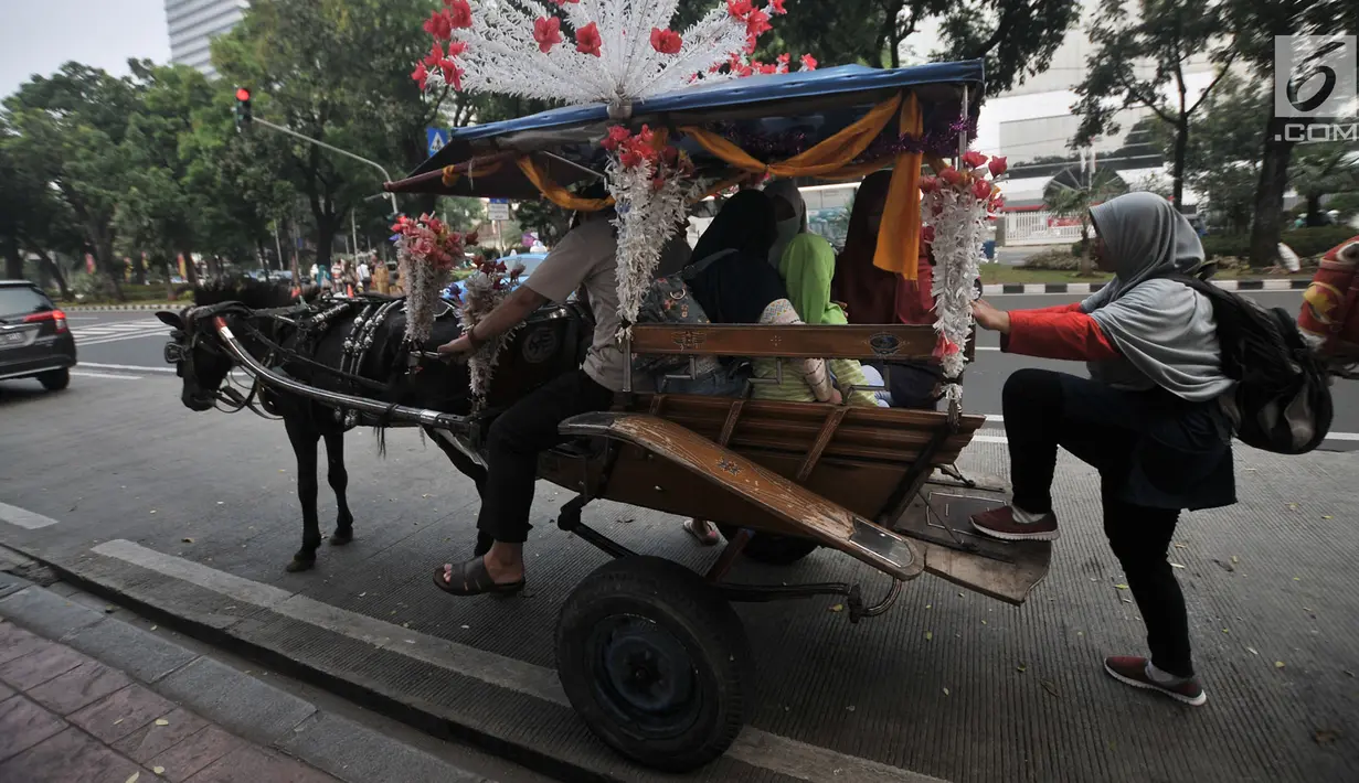 Warga menaiki delman di kawasan Monas, Jakarta, Selasa (3/7). Larangan beroperasi bagi delman di Jakarta Pusat saat Asian Games diberlakukan untuk mengantisipasi penularan virus oleh kuda. (Merdeka.com/Iqbal Nugroho)