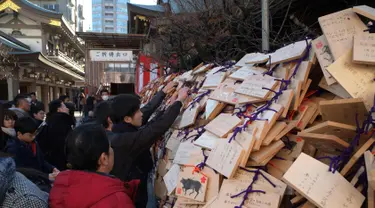 Para pelajar menaruh papan Ema berisi harapan mereka di Kuil Yushima Tenmangu, Tokyo, Jepang, (7/1). Para siswa dan orang tua di Tokyo ramai-ramai mengunjungi Kuil Yushima Tenmangu untuk berdoa sebelum ujian sekolah dimulai. (AFP Photo/Kazuhiro Nogi)