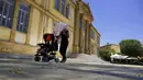Seorang perempuan melindungi dirinya dari sinar matahari dengan payung sambil mendorong bayinya di kereta dorong pada siang hari yang terik di alun-alun Phaneromeni di pusat ibu kota Nicosia, Siprus, Selasa (4/6/2024). (AP Photo/Petros Karadjias)