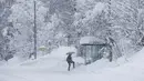 Seseorang mendekati halte bus di jalan yang tertutup salju di Kocevje, dekat Ljubljana Slovenia, Senin (23/1/2023). Badai salju dengan angin kencang telah menghambat lalu lintas di jalan raya utama di Slovenia pada hari Senin dan menyebabkan beberapa bagian negara tanpa listrik untuk sementara waktu. (AP Photo)
