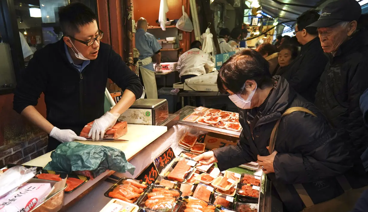 Pedagang melayani pembeli yang sedang mencari bahan-bahan untuk membuat makanan tahun baru atau osechi di Pasar Tsukiji, Tokyo, Jepang, Kamis (26/12/2019). Osechi harus dimasak hingga betul-betul kering agar tahan lama. (AP Photo/Eugene Hoshiko)