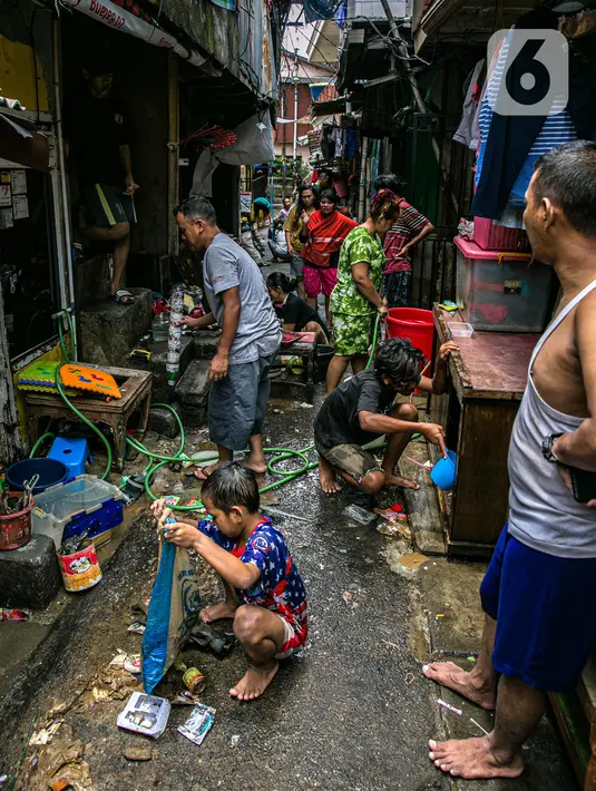 Warga membersihkan barang-barang usai terendam banjir di permukiman kawasan Kampung Melayu, Jakarta, Selasa (9/2/2021). Banjir yang berangsur surut dimanfaatkan warga untuk membersihkan rumah dan barang-barang dari endapan lumpur. (Liputan6.com/Faizal Fanani)