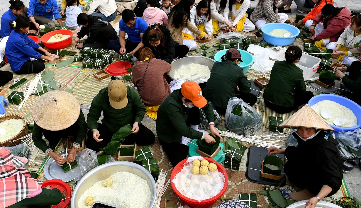 Orang-orang menyiapkan "Banh Chung" atau kue beras tradisional Vietnam untuk amal, menjelang Tahun Baru Imlek atau festival Tet di Pagoda Tam Chuc di provinsi Ha Nam (7/1/2023). Banh Chung adalah kelezatan khas Vietnam yang terbuat dari ketan, daging babi, dan kacang hijau yang dibungkus dengan daun pisang dan dimasak selama 10 jam. (AFP/Nhac Nguyen)