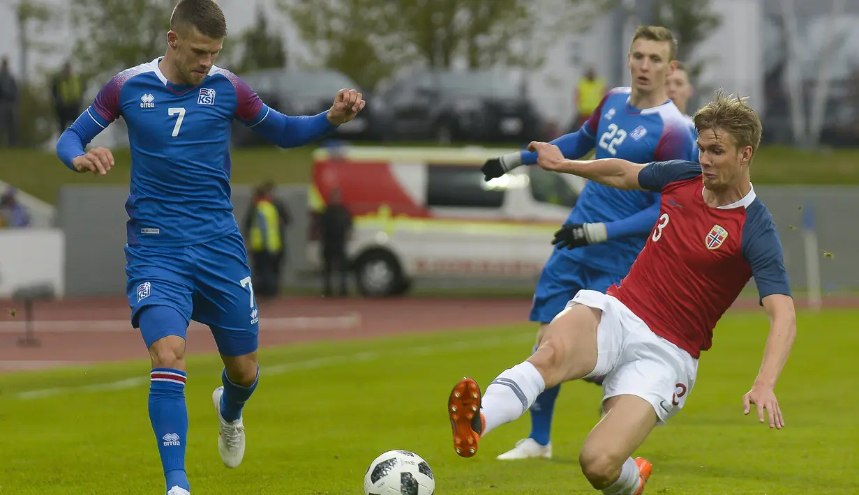 Pemain Islandia, Berg Gudmundsson (kiri) berusaha melewati adangan pemain Norwegia, Kristoffer Ajer pada laga uji coba di Reykjavik, Islandia, (2/6/2018). Islandia kalah dari Norwegia 2-3. (AFP/Haraldur Gudjonsson)