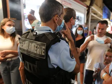 Polisi Prancis berpatroli untuk mengontrol kewajiban penggunaan masker di jalan-jalan Argeles-sur-Mer, Prancis selatan, Rabu (13/8/2020). Pemakaian masker di beberapa area ramai di sekitar Paris merupakan kewajiban sebagai upaya untuk membendung peningkatan tajam infeksi covid-19. (RAYMOND ROIG/AFP)