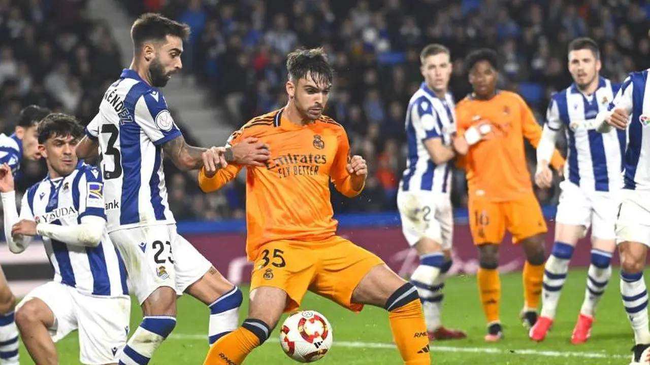 Brais Mendez berebut bola dengan Raul Asencio dalam laga Copa del Rey 2024/2025 antara Real Sociedad vs Real Madrid di Reale Arena, Kamis (27/2/2025) dini hari WIB. (c) AP Photo/Miguel Oses