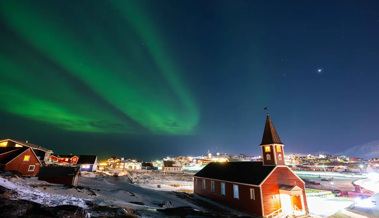 Untuk diketahui, Aurora Borealis hanya terjadi di wilayah lintang tinggi bumi bagian Utara. Tampak dalam foto, Aurora Borealis menerangi langit di atas katedral The Nuuk di Nuuk, Greenland, pada 23 Januari 2026. (Jonathan NACKSTRAND/AFP)