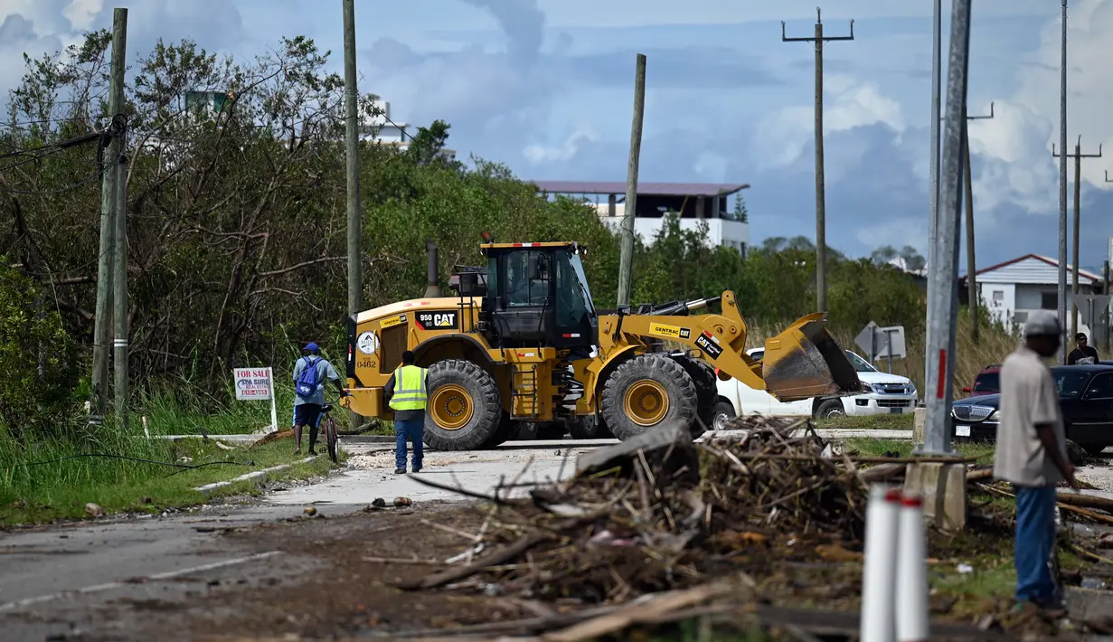 Pekerja memindahkan pohon dan cabang yang tumbang dari jalan raya setelah Badai Lisa di Belize City, Belize, 3 November 2022. Badai Tropis Lisa menyebabkan banjir dan membuat sebagian negara itu menjadi gelap gulita. (Johan ORDONEZ/AFP)