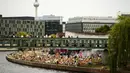 Orang-orang menikmati hari musim panas di sebuah bar di sungai Spree di pusat Berlin, Jerman, Minggu (19/6/2022). Orang-orang berbondong-bondong ke taman dan kolam renang di seluruh Eropa Barat untuk sedikit mendinginkan tubuh mereka dari gelombang panas awal. (AP Photo/Markus Schreiber)