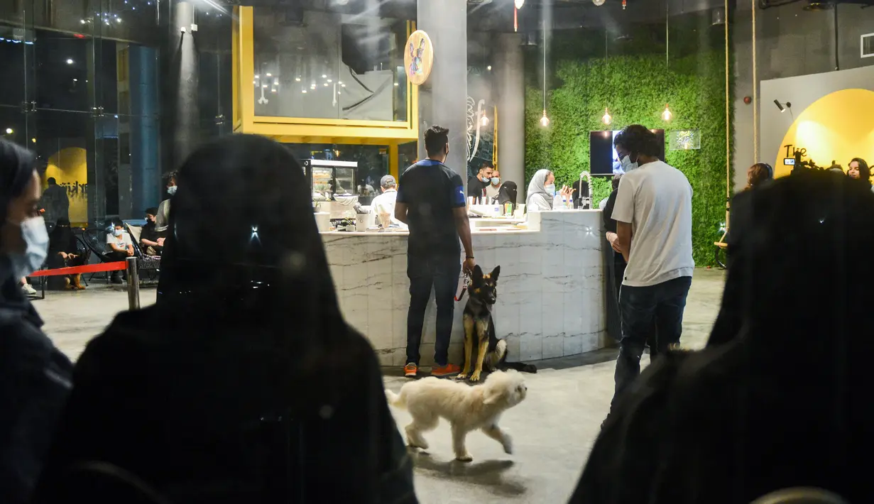 Pemilik anjing memesan di kafe "Barking Lot" di kota pesisir Khobar, Arab Saudi pada 25 September 2020. Pemilik anjing di Arab Saudi kini dapat menikmati secangkir kopi bersama hewan kesayangan mereka di kafe baru, sekaligus yang pertama di negara konservatif itu. (FAYEZ NURELDINE/AFP)