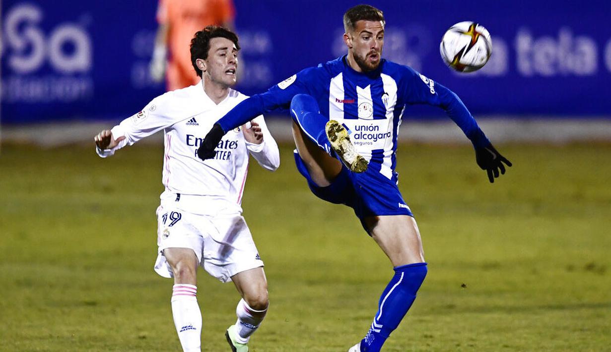 Pemain Real Madrid, Alvaro Odriozola, berebut bola dengan pemain Alcoyano, Ramon, pada laga Copa del Rey di Stadion El Collao, Rabu (20/1/2021). Real Madrid takluk dengan skor 2-1. (AP/Jose Breton)