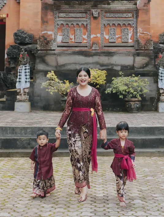 Sedah Mirah Nasution menduplikasi penampilan sang ibu dengan mengenakan kebaya Bali dan kain endek. Kain berwarna merah pun diaplikasikan sebagai ikat pinggang, mirip sang ibu. (instagram/doleytobing)