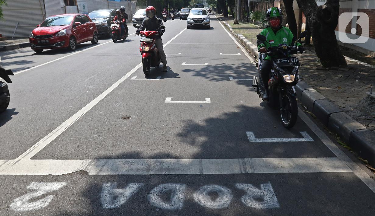 Pembatas Jarak Bagi Pengendara Motor: Pengendara motor berhenti pada garis pembatas antarpengendara di kawasan Hang Tuah Raya, Jakarta, Selasa (16/6/2020). Garis itu untuk membatasi jarak antarpengendara guna mencegah penyebaran COVID-19. (Liputan6.com/Herman Zakharia)