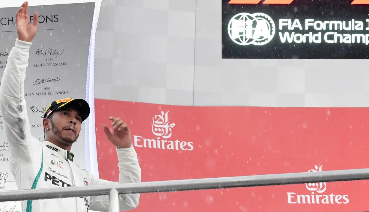 Pembalap Mercedes, Lewis Hamilton merayakan kemenangan di atas podium setelah menjuarai balapan F1 GP Jerman di Sirkuit Hockenheim, Minggu (22/7). Kemenangan ini diraih secara dramatis karena Hamilton mengawali balapan dari urutan ke-14. (AP/Jens Meyer)
