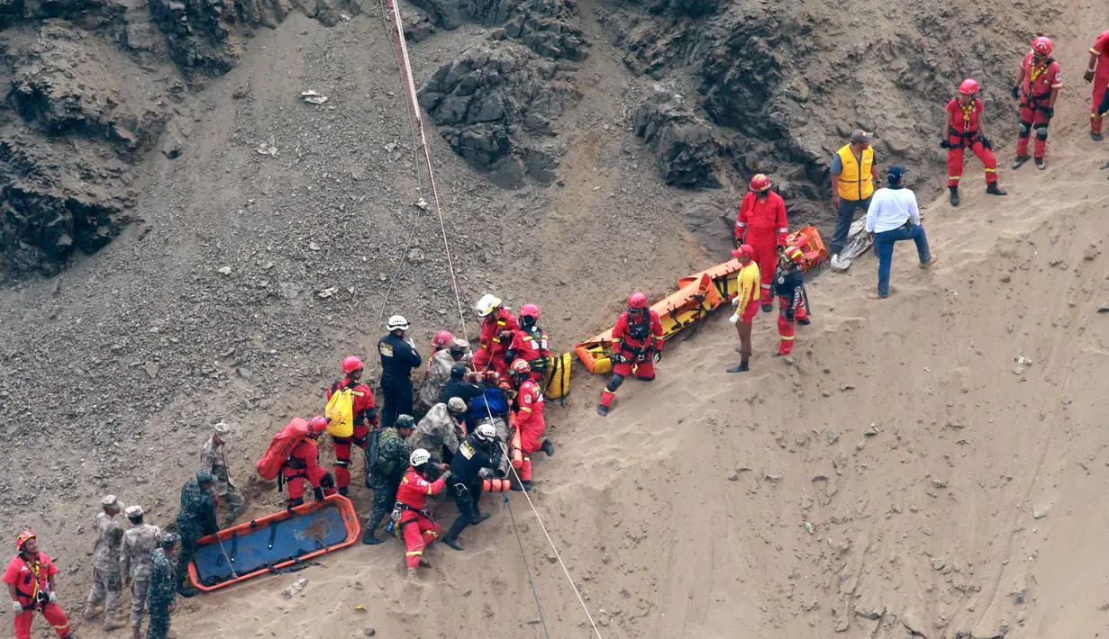 Petugas penyelamat mengelilingi tubuh salah satu korban terluka setelah sebuah bus jatuh dari tebing di Pasamayo, Peru, Selasa (3/1). Sebelum terjun ke jurang, bus sempat bertabrakan dengan sebuah truk trailer. (Vidal Tarky, Andina News Agency via AP)