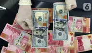 Karyawan menunjukkan uang dolar AS dan rupiah di Jakarta, Rabu (30/12/2020). Nilai tukar rupiah di pasar spot ditutup menguat 80 poin atau 0,57 persen ke level Rp 14.050 per dolar AS. (Liputan6.com/Johan Tallo)